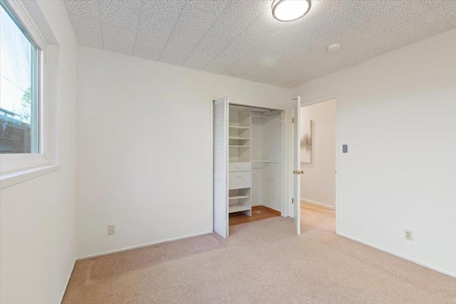 unfurnished bedroom with light carpet and a closet