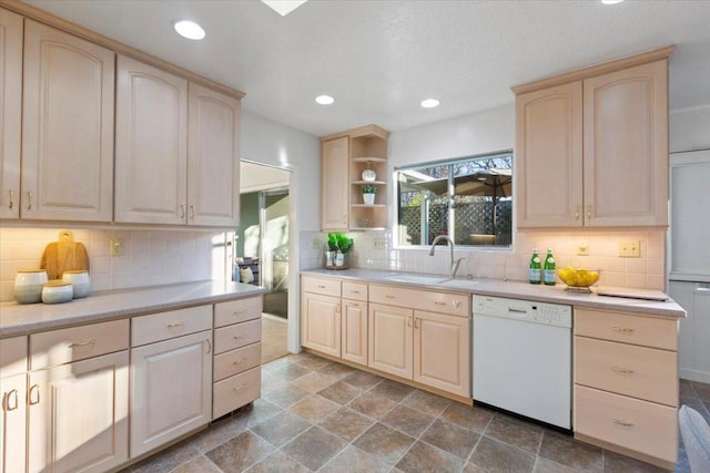 kitchen featuring backsplash, dishwasher, sink, and light brown cabinets