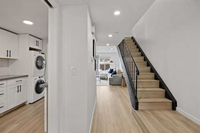 interior space with white cabinetry, light hardwood / wood-style floors, and stacked washing maching and dryer