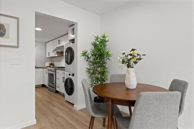 laundry room featuring stacked washer / drying machine and light hardwood / wood-style floors