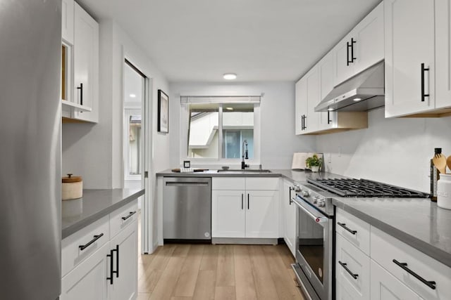 kitchen featuring appliances with stainless steel finishes, sink, light hardwood / wood-style flooring, and white cabinets