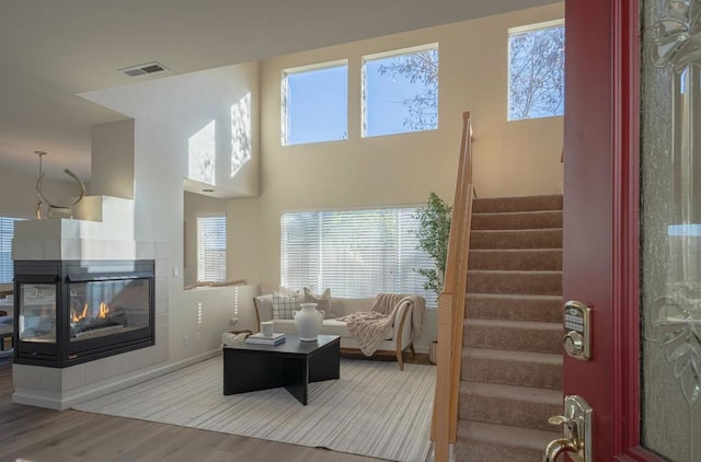 living room with plenty of natural light, a towering ceiling, hardwood / wood-style floors, and a fireplace