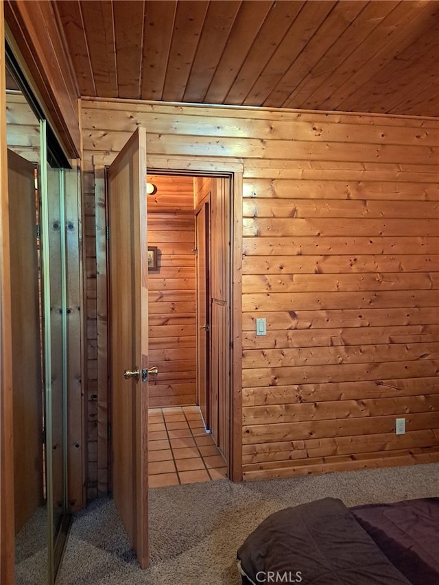 hall featuring wood ceiling, light colored carpet, and wood walls