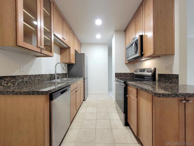 kitchen with light tile patterned flooring, stainless steel appliances, sink, and dark stone counters