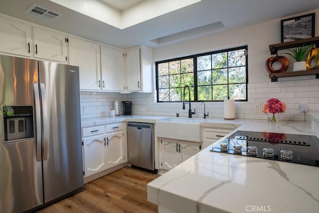 kitchen with white cabinetry, light stone counters, visible vents, and appliances with stainless steel finishes