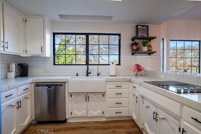 kitchen featuring a healthy amount of sunlight, black electric stovetop, stainless steel dishwasher, white cabinets, and a sink
