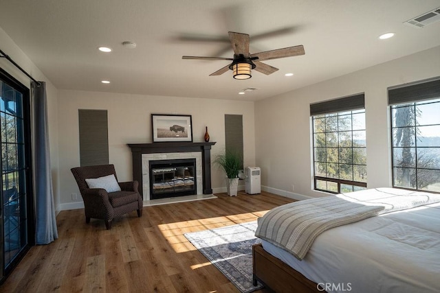 bedroom with visible vents, wood finished floors, recessed lighting, baseboards, and a tile fireplace