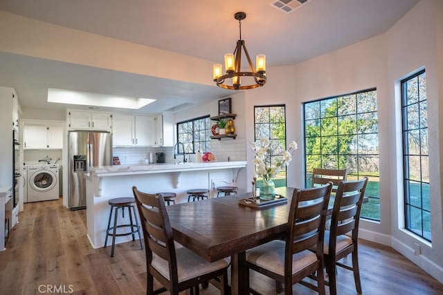 dining space featuring a chandelier, visible vents, light wood-style flooring, and baseboards