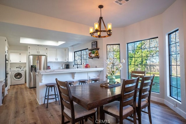 dining room with an inviting chandelier, light wood-style floors, visible vents, and baseboards