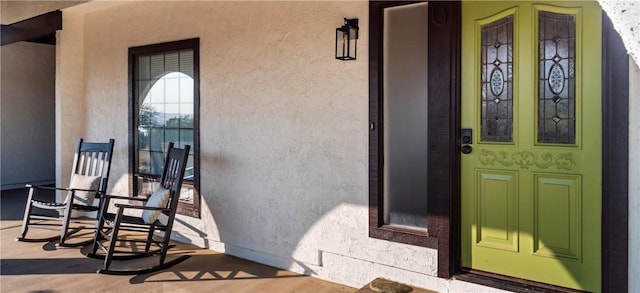 doorway to property with a porch and stucco siding