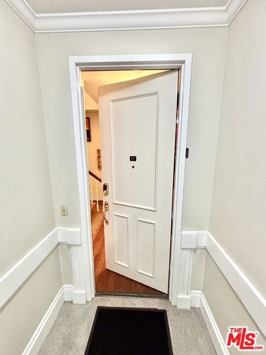 doorway to outside with light carpet and crown molding