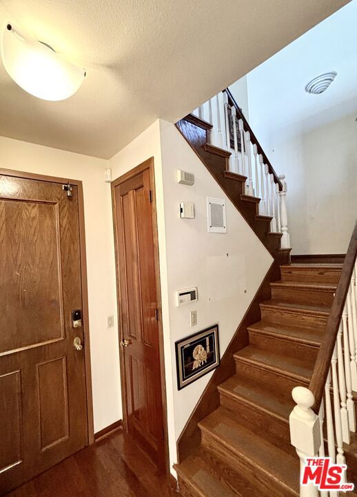 stairs with hardwood / wood-style flooring and a textured ceiling