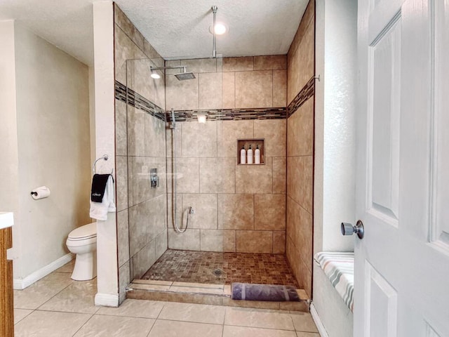 bathroom featuring vanity, a tile shower, tile patterned floors, and a textured ceiling