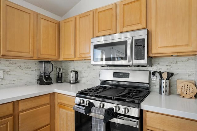 kitchen with appliances with stainless steel finishes, light brown cabinetry, and backsplash