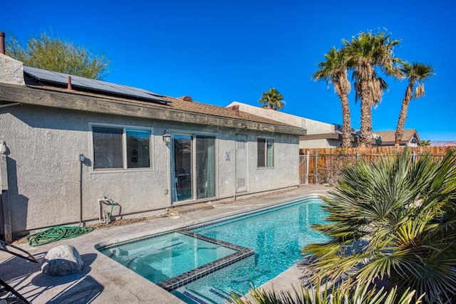 back of property featuring a swimming pool with hot tub and solar panels