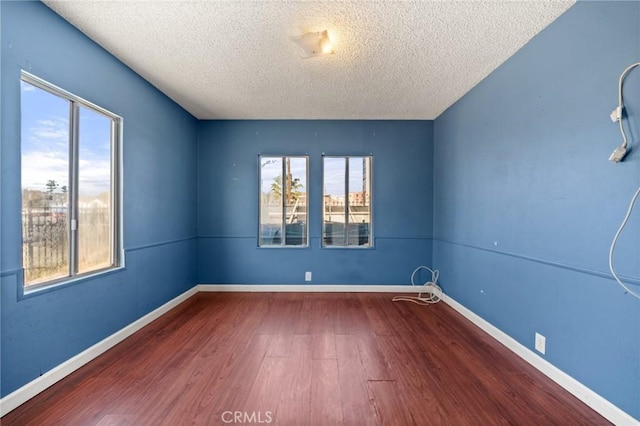 unfurnished room with hardwood / wood-style flooring, plenty of natural light, and a textured ceiling