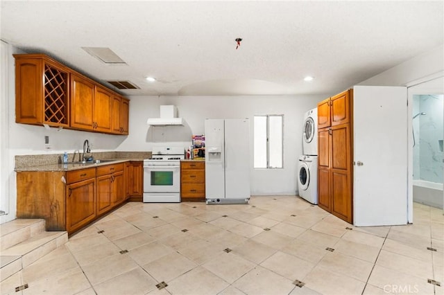 kitchen with stacked washer / drying machine, white appliances, and sink