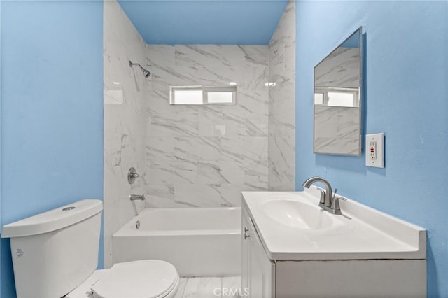 full bathroom featuring vanity, tiled shower / bath combo, and toilet