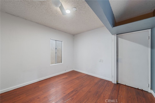 empty room with ceiling fan, dark hardwood / wood-style floors, and a textured ceiling