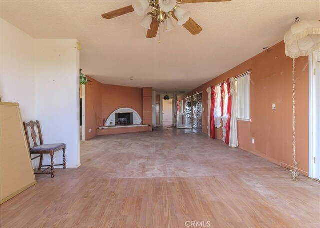 unfurnished living room with ceiling fan, wood-type flooring, and a textured ceiling