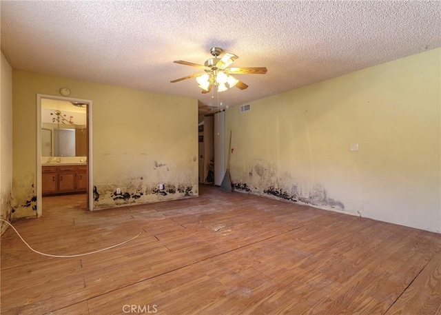 spare room with a textured ceiling, light hardwood / wood-style floors, and ceiling fan