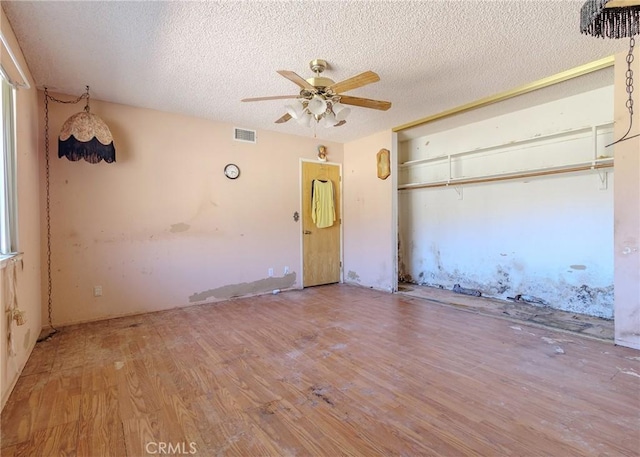 unfurnished bedroom with wood-type flooring, a textured ceiling, ceiling fan, and a closet