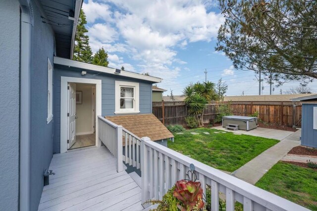 wooden deck featuring a lawn and a hot tub