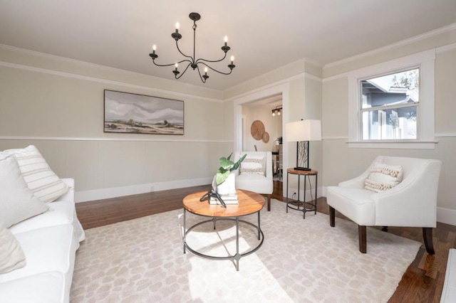 living area with hardwood / wood-style flooring, ornamental molding, and a chandelier