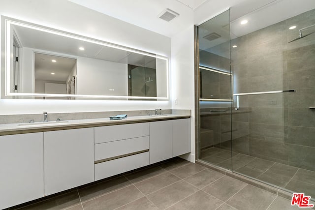 bathroom featuring a shower with door, vanity, and tile patterned flooring