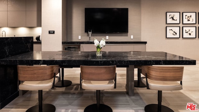 bar with gray cabinetry, dark stone counters, and light tile patterned flooring