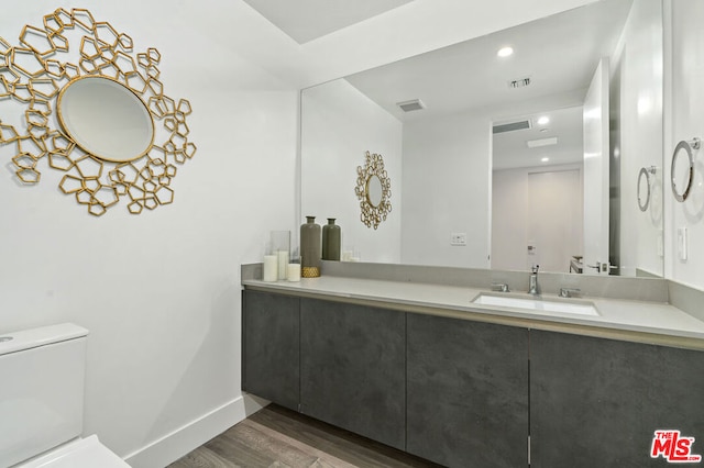 bathroom with vanity, wood-type flooring, and toilet