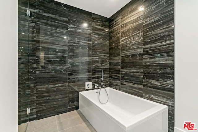 bathroom with tile walls, tile patterned flooring, and a tub