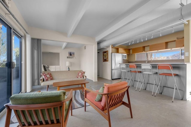 interior space featuring stainless steel refrigerator, a kitchen bar, and beamed ceiling