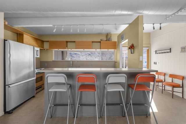 kitchen with stainless steel refrigerator, range, a breakfast bar, and a kitchen island