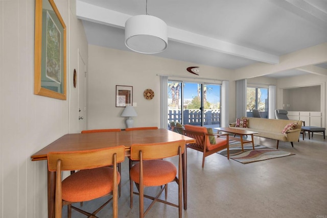 dining area featuring beamed ceiling and concrete floors