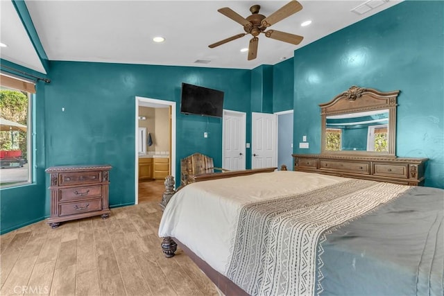 bedroom featuring ceiling fan, lofted ceiling, connected bathroom, and light hardwood / wood-style floors