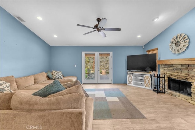 living room featuring french doors, ceiling fan, and a stone fireplace