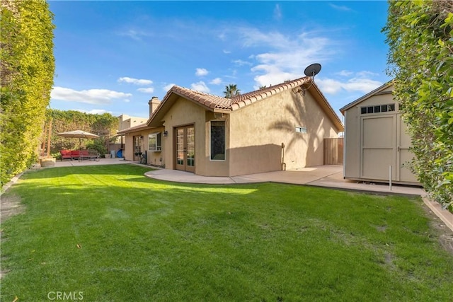 rear view of property featuring french doors, a storage shed, a yard, and a patio