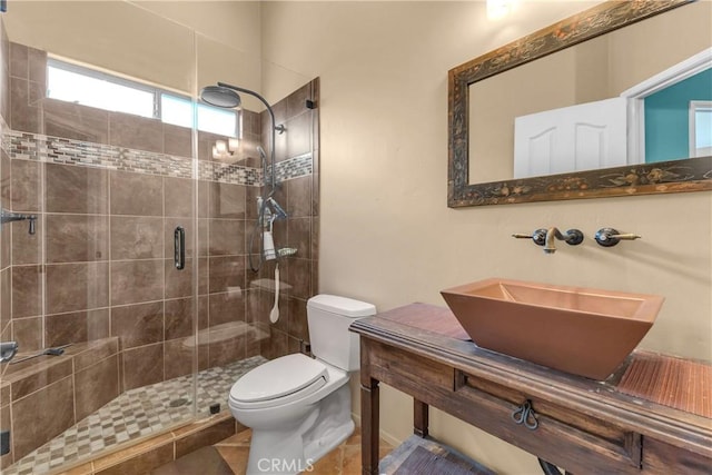 bathroom with tile patterned flooring, vanity, a shower with shower door, and toilet