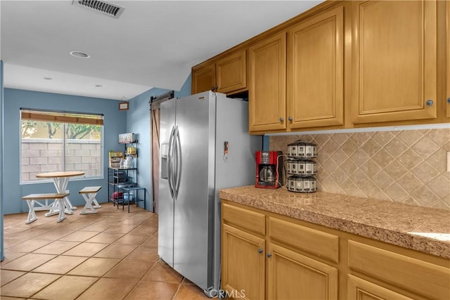 kitchen featuring tasteful backsplash, light tile patterned floors, and stainless steel fridge with ice dispenser