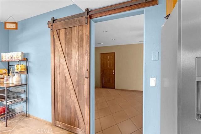 corridor with a barn door and light tile patterned floors