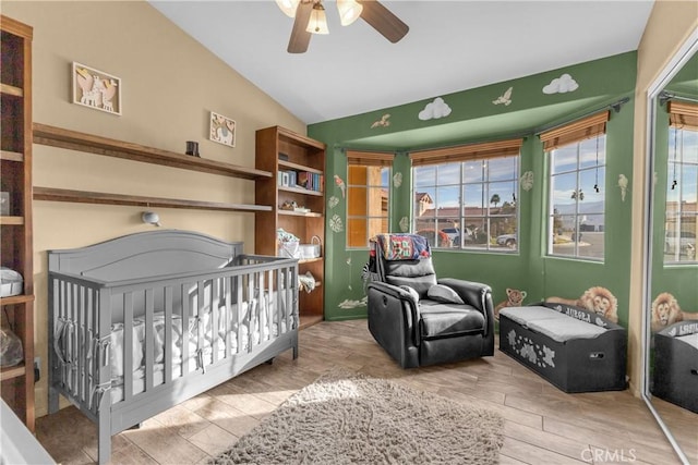 bedroom with lofted ceiling, a nursery area, and ceiling fan