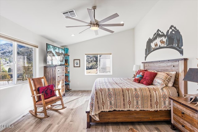 bedroom with multiple windows, hardwood / wood-style flooring, vaulted ceiling, and ceiling fan