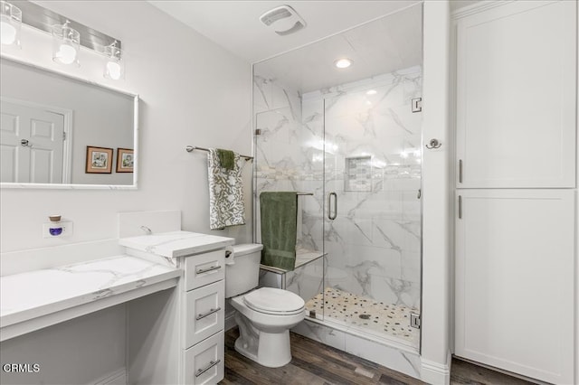 bathroom with vanity, hardwood / wood-style floors, a shower with shower door, and toilet