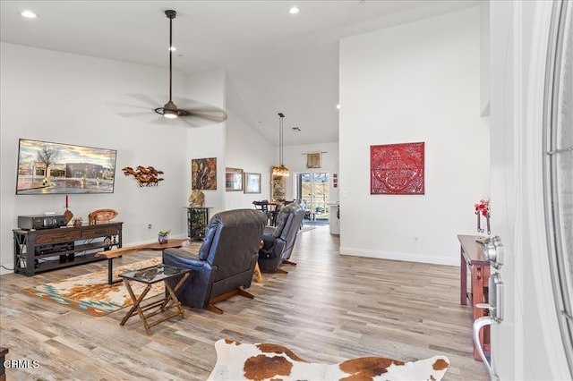 living room with ceiling fan, high vaulted ceiling, and light wood-type flooring