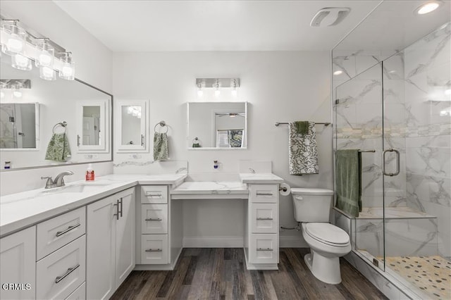 bathroom with hardwood / wood-style flooring, toilet, vanity, and walk in shower