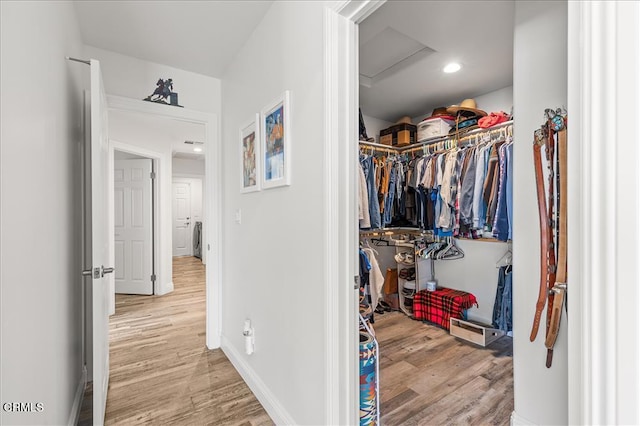 walk in closet with washer / dryer and light hardwood / wood-style floors