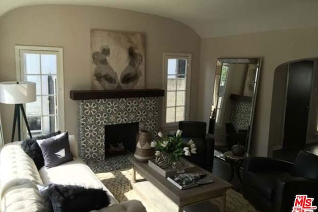 living room featuring lofted ceiling and a tile fireplace