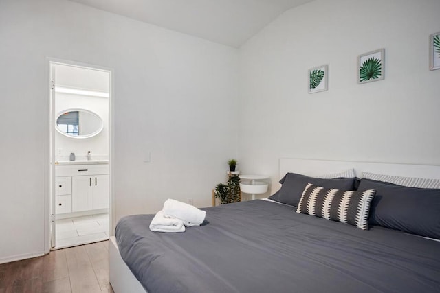 bedroom with lofted ceiling, ensuite bathroom, and wood-type flooring