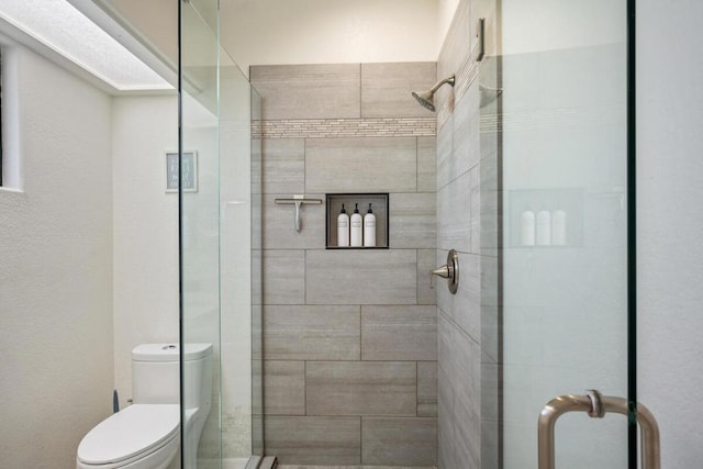 bathroom featuring a shower with shower door and toilet